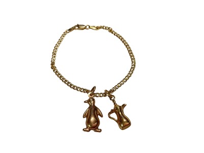 Lot 103 - 18ct gold flat curb link chain bracelet with 9ct gold penguin charm and yellow metal coffee pot charm