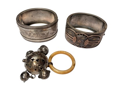 Lot 65 - Two Victorian silver hinged cuff bangles, both with engraved floral scroll decoration, together with an Edwardian silver babies rattle (3)