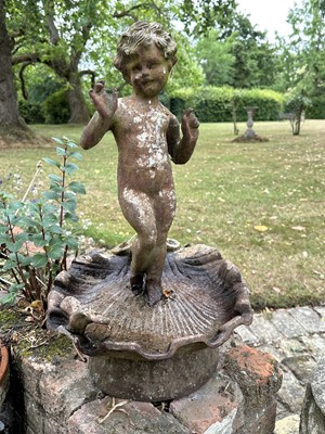 Lot 1279 - Antique cast iron bird bath mounted with a putto standing with a shell, a bird to the rim, 56cm high