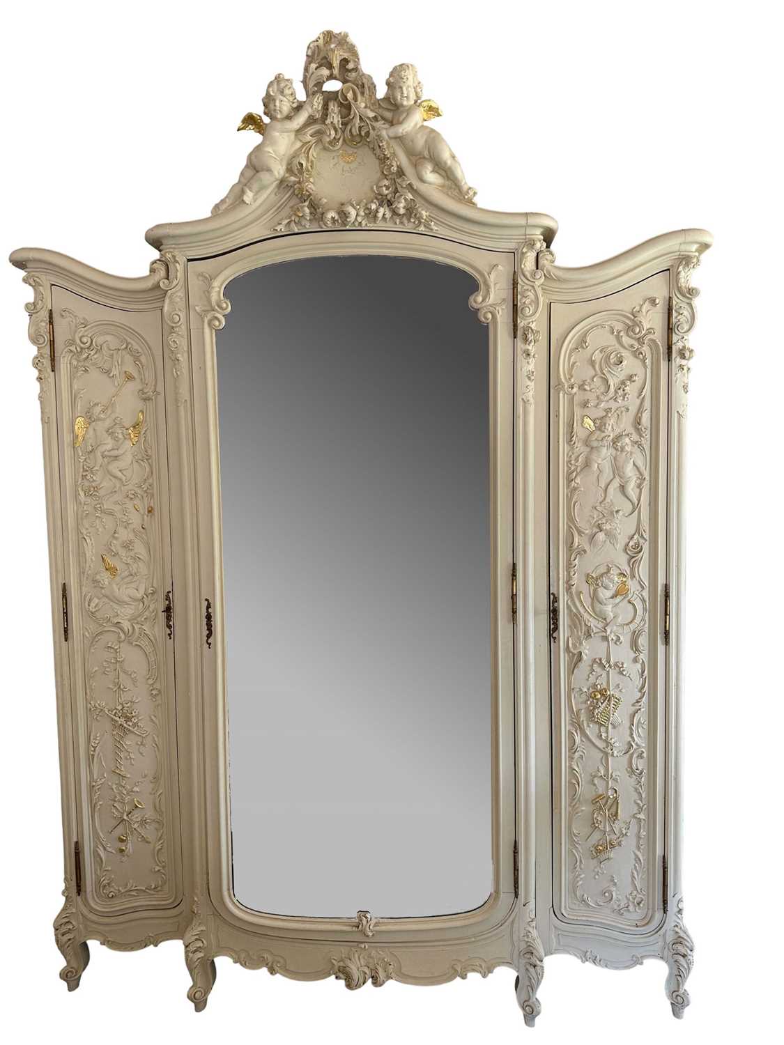 Lot 1353 - An impressive antique rococo revival wardrobe, the central mirrored doors enclosing five flanked by two cupboards, decorated with putti and foliate trailing decoration highlighted in gilt, on sc...