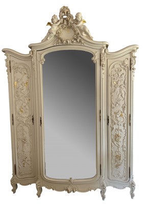 Lot 1353 - An impressive antique rococo revival wardrobe, the central mirrored doors enclosing five flanked by two cupboards, decorated with putti and foliate trailing decoration highlighted in gilt, on sc...
