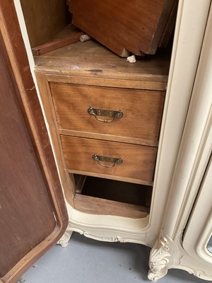 Lot 1353 - An impressive antique rococo revival wardrobe, the central mirrored doors enclosing five flanked by two cupboards, decorated with putti and foliate trailing decoration highlighted in gilt, on sc...