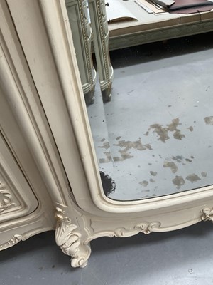 Lot 1353 - An impressive antique rococo revival wardrobe, the central mirrored doors enclosing five flanked by two cupboards, decorated with putti and foliate trailing decoration highlighted in gilt, on sc...