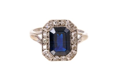 Lot 449 - Sapphire and diamond cluster ring with a rectangular step cut dark blue sapphire measuring approximately 9.7mm x 6.9mm surrounded by an octagonal border of single cut diamonds in 18ct white gold...