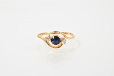 Lot 389 - Edwardian sapphire and diamond three stone ring with a blue mixed-cut sapphire flanked by two old cut diamonds in millegrain crossover setting on 18ct gold shank