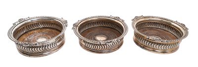 Lot 246 - Three George III silver bottle coasters, with wrythen decoration, gadrooned shell and leaf rims