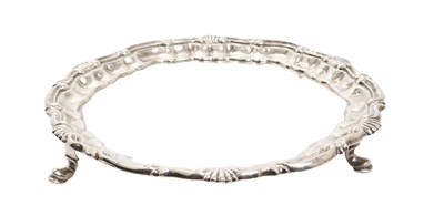 Lot 274 - George II silver waiter of circular form with shell and scroll border, on three hoof feet