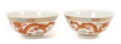Lot Pair of Chinese porcelain bowls, 19th / 20th century, finely decorated in enamels with dragons chasing the pearl amongst clouds, waves below and a Greek key border, iron-red six character Guangxu...