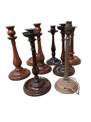 Lot 2585 - Collection of treen candlesticks, 19th century and later, one brass lamp base