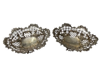 Lot 100 - Pair of Victorian silver bon bon dishes of oval form, with pierced and embossed decoration and each with engraved armorials and raised on oval feet, (London 1892)