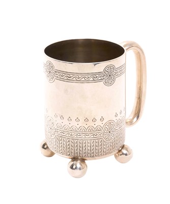 Lot 245 - Victorian silver christening mug of cylindrical form with engraved decoration and raised on four ball feet, (London 1877), maker George Adams, 10cm in overall height, 6ozs.