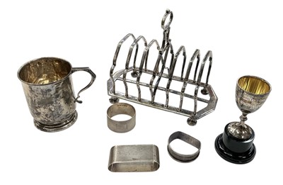Lot 904 - George V silver christening mug, (Birmingham 1934), silver trophy, silver napkin rings and silver plated toast rack.