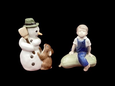 Lot 1218 - Royal Copenhagen porcelain figure - Snowman holding a broom with rabbit on hind legs no. 017, together with another of a Boy sitting on a gourd no. 4539