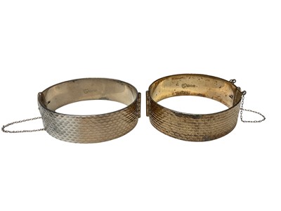 Lot 138 - Pair of 1960s silver hinged bangles with a textured finish, one 22ct on silver (London 1966)