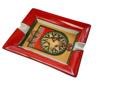 Lot 1258 - Hermes, Paris- porcelain ashtray in the red compass pattern, with leather covered base, 20cm in length.