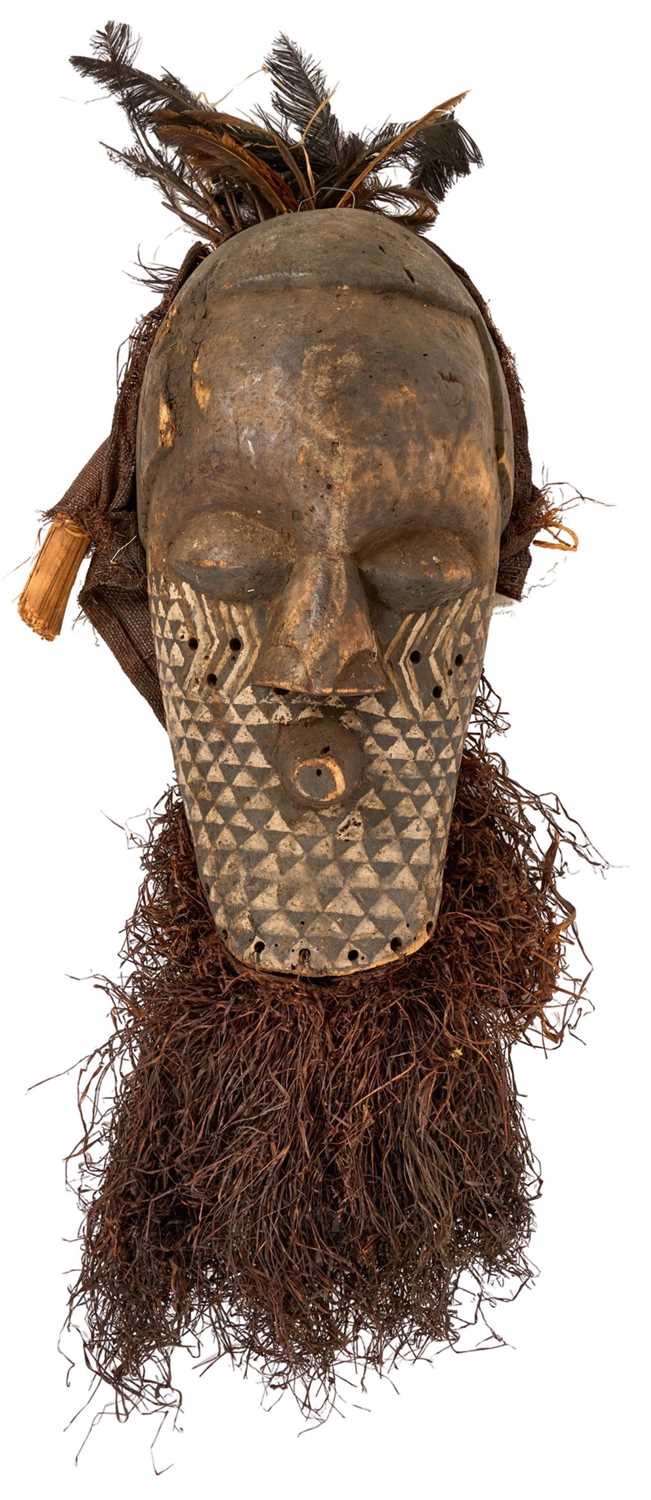 Lot 754 - Antique Kuba Pwoom Itok mask, with stylised features and white pigment, with feathers and raffia, the wooden part approximately 48cm high