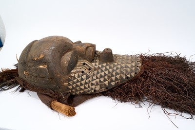 Lot 754 - Antique Kuba Pwoom Itok mask, with stylised features and white pigment, with feathers and raffia, the wooden part approximately 48cm high
