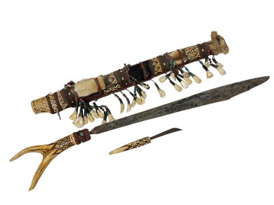 Lot 759 - Dyak headhunter sword, with antler handle and embellished with polychrome ornament and hung with teeth, 68cm long, together with cannibal fork. (2)