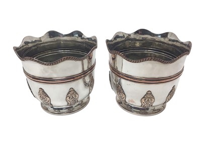 Lot 281 - Pair of late Victorian silver plated wine coolers / jardinières with gadrooned borders and applied panels of scroll decoration, each 17.8cm in overall height.