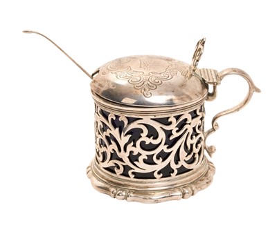 Lot 314 - Victorian silver mustard pot of drum form with pierced decoration and blue glass liner, hinged lid with engraved decoration and armorial, (London 1842).