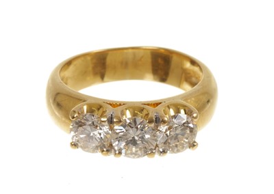 Lot Diamond three-stone ring with three brilliant cut diamonds in four claw setting on wide yellow gold shank. Estimated total diamond weight approximately 1.50cts