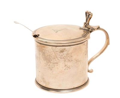 Lot 231 - George V silver mustard pot of drum form with scroll handle, hinged cover with engraved armorial and blue glass liner, (London 1913), maker William Comyns, together with an earlier silver fiddle...