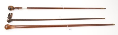 Lot 809 - Early 20th century New Zealand specimen wood cane, with silver collar inscribed Port Chalmers, 1913, together with similar stick and an ornately carved cane with serpent and heart motifs. (3)