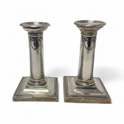 Lot 299 - Pair of late Victorian silver candlesticks on square bases with beaded borders (London 1900)
