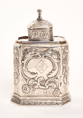 Lot George I silver tea caddy of elongated octagonal form with sliding top and detachable lid, all over later decorated with repousse floral and scroll motifs, the cartouche with engraved crest (Lon...