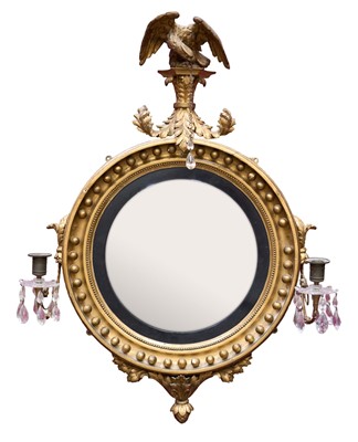 Lot 1356 - Regency giltwood convex wall mirror, central circular frame with ball mounts, surmounted by an eagle with foliate apron. The sides issuing a pair of scroll branches with cut glass drip pans and...