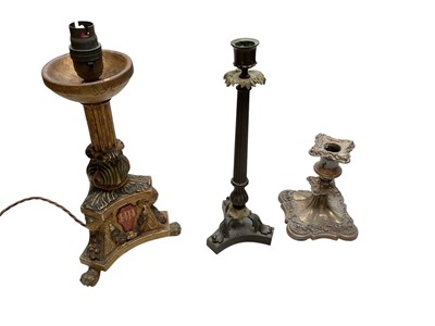 Lot 5028 - Regency bronze candlestick, with column stem and scroll feet on a shaped base, together with a gilt candlestick converted to a lamp and a silver plated candlestick (3)