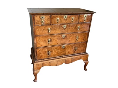 Lot 1364 - Queen Anne walnut and feather-banded chest on later stand, having three short over three long graduated drawers, raised on later stand with shaped apron and cabriole legs on pad feet, 107cm wide...