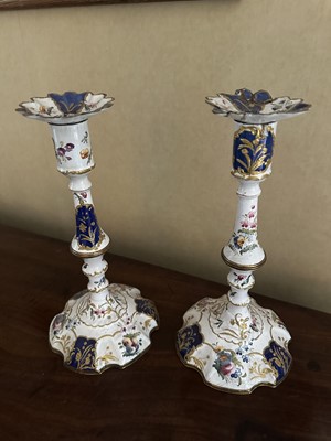 Lot 1695 - Pair of 18th century Bilston enamel candlesticks, knopped form with removable petalled sconces and blue and gilt reserves and scattered floral ornament on spread bases, 25.5 high