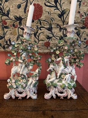 Lot 1766 - Pair of 18th century English porcelain candlesticks, each with cherubic figures and livestock surrounded by bocage