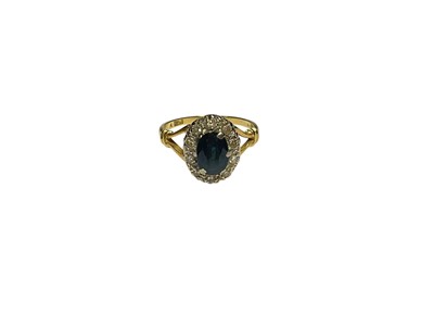 Lot 91 - Sapphire and diamond cluster ring with an oval mixed cut blue sapphire surrounded by a border of single cut diamonds in platinum setting on 18ct gold shank