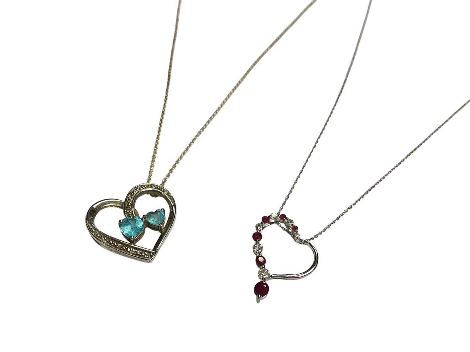 Lot 53 - Diamond and ruby 9ct white gold heart pendant on chain and a diamond and blue topaz silver heart shaped pendant on chain (2)