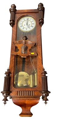 Lot 164 - Late 19th century Vienna wall clock with enamel dial, twin brass cased weights and brass faced pendulum in walnut case with turned finials, 112 cm high. Key, pendulum and weights present