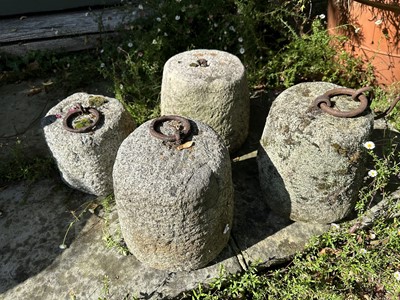 Lot 1934 - Four antique granite weights, three with cast iron rings, 24cm high