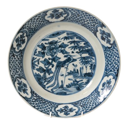 Lot 1905 - 16th / 17th century Chinese blue and white Swatow / Zhangzhou dish, painted with a phoenix amongst foliage, the border with floral panels on a fish scale ground, 28.5cm diameter