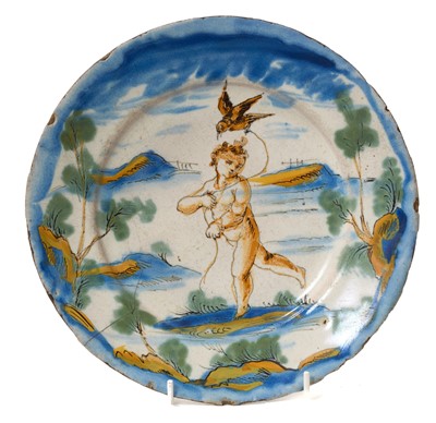 Lot 1914 - Italian maiolica dish, possibly 18th century, painted with a cherub holding a bird on a string, in a landscape setting, marked with a sun to the base and the initials N.S, 23.5cm diameter