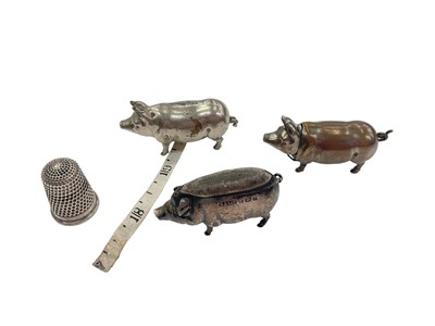 Lot 909 - Edwardian miniature silver pig pin cushion (Birmingham 1905), together with a miniature plated pig vesta and tape measure, and a silver thimble (4)