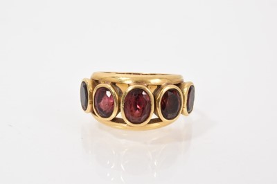 Lot 722 - Garnet five stone ring with five oval mixed cut graduated garnets in a rub over setting within a split gold shank, stamped 18K. Ring size P