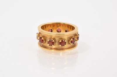 Lot 723 - Garnet eternity-style ring with eleven round mixed cut garnets in a four claw setting within a thick gold band, stamped 750