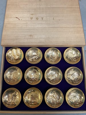 Lot 354 - Set of twelve Chinese gold plated stainless steel dishes depicting zodiac animals, in a fitted wooden case
