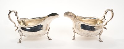 Lot 433 - Pair of good quality George VI silver sauce boats of helmet form with scroll handles, each raised on three hoof feet, (London 1937 & 1938), maker Goldsmiths & Silversmiths Company Ltd, e...
