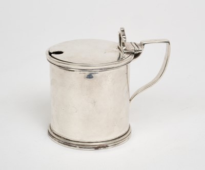 Lot 438 - George VI silver mustard pot of drum form, with hinged cover, shaped thumb piece, angular handle and blue glass liner to interior, (London 1939), maker Goldsmiths and Silversmiths Company, 7.2cm...