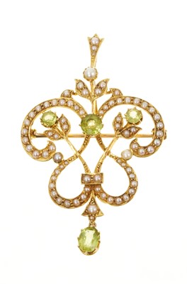 Lot 706 - Edwardian Art Nouveau peridot and seed pearl pendant / brooch with seed pearl floral scrolls and mixed-cut peridots, in gold setting with detachable pendant fitting, 52mm.