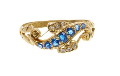 Lot 708 - Late Victorian sapphire and diamond ring with seven graduated mixed-cut blue sapphires in a scroll design with rose cut diamonds to the leaves, (Chester 1901) Ring size Q.