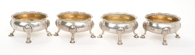 Lot 469 - Set of four George III silver salts of oval form, with gadrooned borders and engraved armorial crests, on shell mounted hoof feet, (London 1765), maker Robert and David Hennell, each 7.6cm in length.