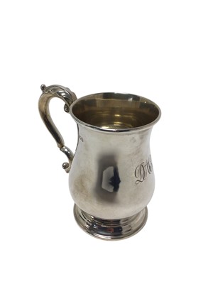 Lot 471 - Edwardian silver mug of baluster form, with engraved initials and leaf mounted scroll handle, raised on a circular foot, (London 1909), maker Edward Barnard & Sons Ltd, 13.4cm overall height...